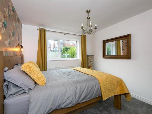 Schlafzimmer mit einem Bett, einem Fenster und einem Spiegel in der Unterkunft Pass the Keys Modern Coastal Home in Bull Bay in Amlwch