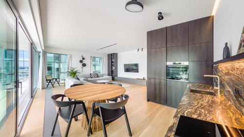 cocina y sala de estar con mesa de madera y sillas en Flatbook - City Center Apartments Yacht Park, en Gdynia