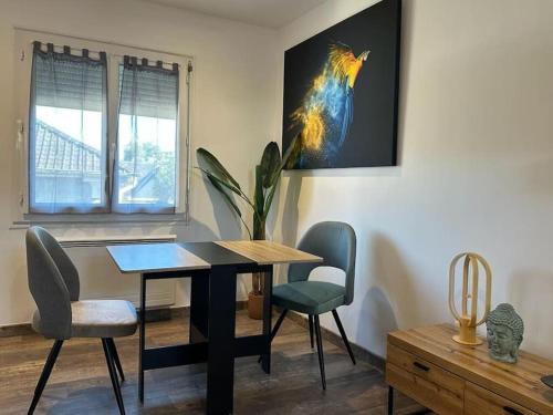une table à manger avec des chaises et une photo d'un oiseau dans l'établissement Nid douillet, à Pau