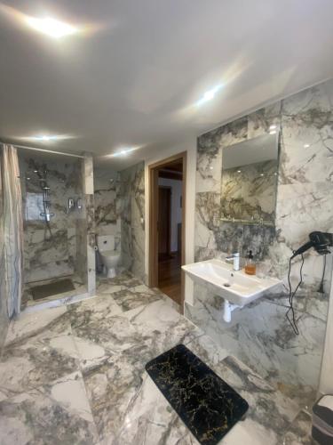 a marble bathroom with a sink and a mirror at Penzión Velická vináreň in Poprad