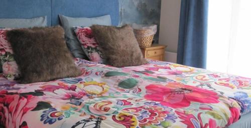 uma cama com um cobertor florido e almofadas em Het Schuurhuis em Stadskanaal