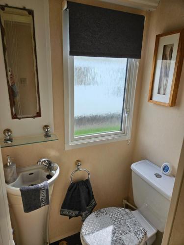 a bathroom with a sink and a toilet and a window at Rhuddlan Salty Smiles in Rhuddlan