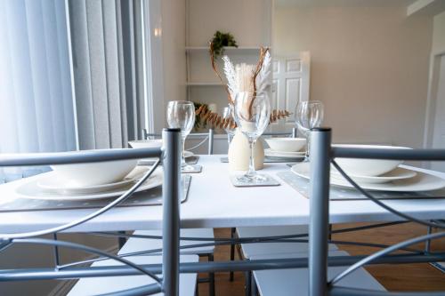 uma mesa de jantar branca com cadeiras e copos em Entire House-Merseyside-Liverpool em Birkenhead