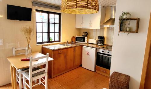 uma cozinha com uma mesa e uma cozinha com uma mesa e cadeiras em Cantinho de Milfontes Jacuzzi em Vila Nova de Milfontes