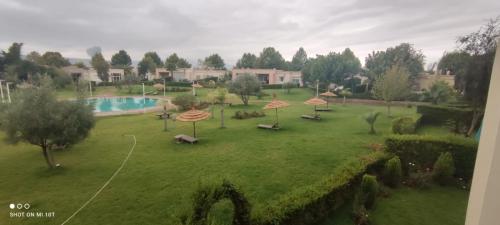 a green yard with umbrellas and a swimming pool at Résidence du golf in Fez