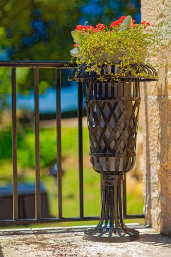 a vase filled with red flowers on a balcony at Hameau du Château de Giverzac, gîtes luxueuses in Domme