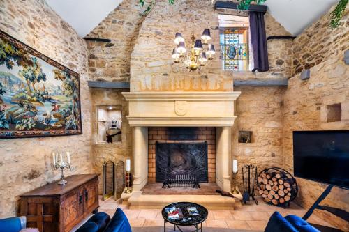 a living room with a stone wall with a fireplace at Hameau du Château de Giverzac, gîtes luxueuses in Domme