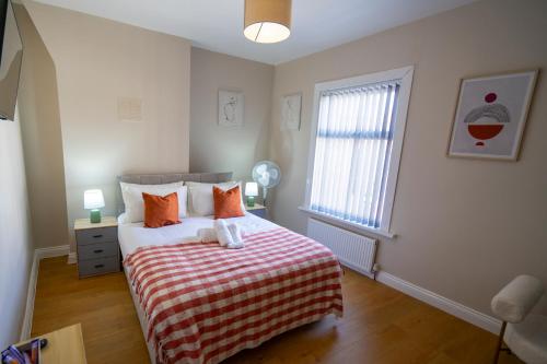 a bedroom with a bed with a striped blanket and a window at Entire House-Merseyside-Liverpool in Birkenhead
