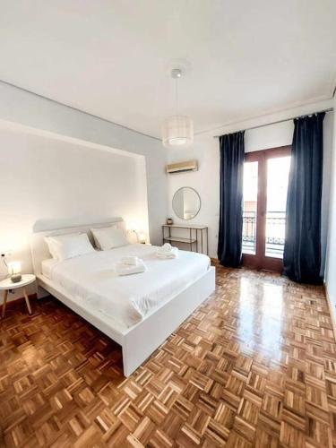 a bedroom with a white bed and a wooden floor at Olvia A breath away from Old Town Center in Rethymno