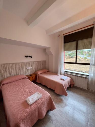 two beds in a room with a window at Hostal mesón del cinca in El Grado