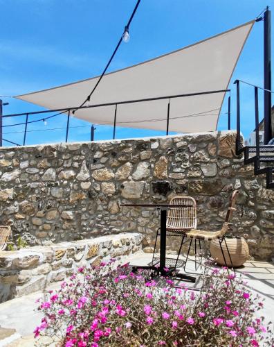 a stone wall with a table and chairs and flowers at Pyrgi Cretan Living & Spa in Pírgos