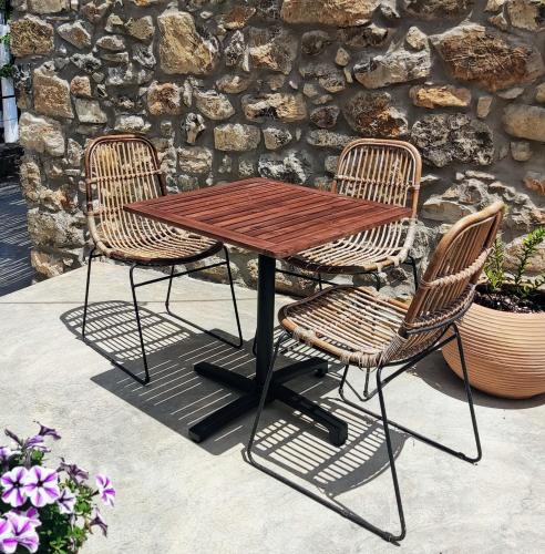 a wooden table and two chairs sitting next to a stone wall at Pyrgi Cretan Living & Spa in Pírgos