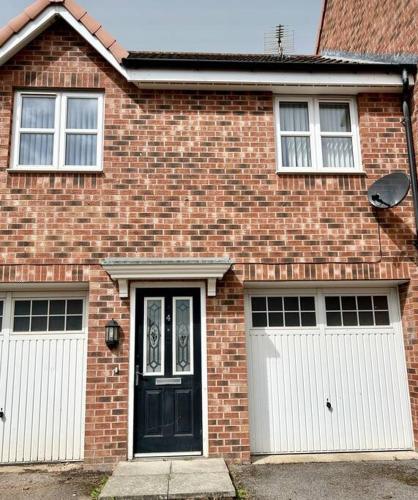 a brick house with two garages and a black door at The Gainsborough Mews-stylish & modern (sleeps 3) in Lincolnshire