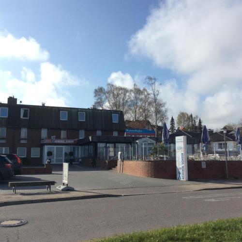 a parking lot in front of a building with a bench at Hotel Admiral Scheer in Laboe