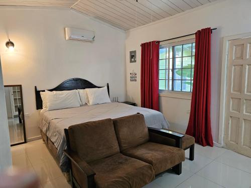 a bedroom with a bed and a couch and a window at Roots Cafe Rooms in Negril