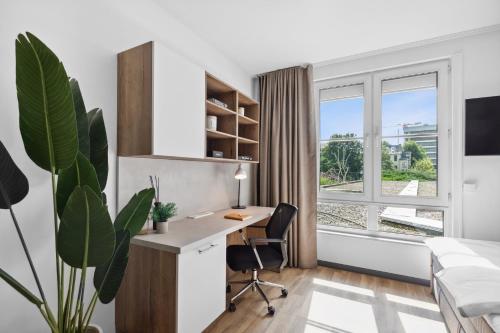 Home and CoLiving Bonn I Aparthotel I Soft Opening في بون: مكتب فيه مكتب وسرير ونافذة