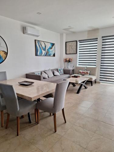 a dining room with a table and chairs and a couch at Rosarito Beach condominio in Rosarito