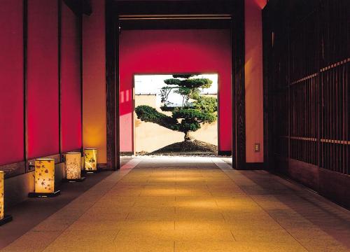 a hallway with a tree in a room with red walls at Seaside Hotel Mimatsu Ooetei in Beppu