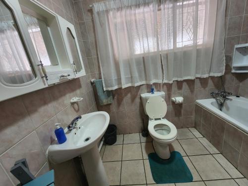 a bathroom with a toilet and a sink and a tub at Midway Overnight Rooms in Kimberley