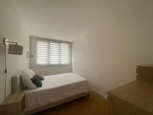 um quarto branco com uma cama e uma janela em 2pièces meublé Proche Paris et métro em Maisons-Alfort