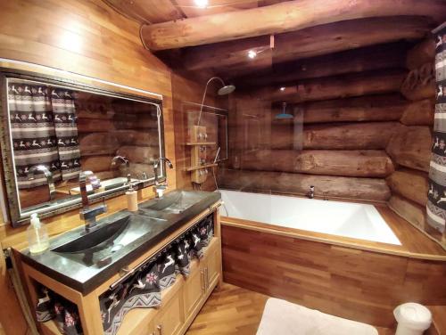 a bathroom with a tub and a sink and a bath tub at Buckey Lodge, à 2 minutes des cascades de Tendon in Tendon