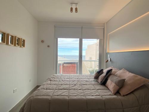 Un dormitorio con una cama grande con una ventana grande. en AZUL - Pto Madryn, en Puerto Madryn