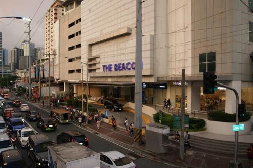 una concurrida calle de la ciudad con coches aparcados frente a un edificio en The Beacon Makati by mvmtransient en Manila