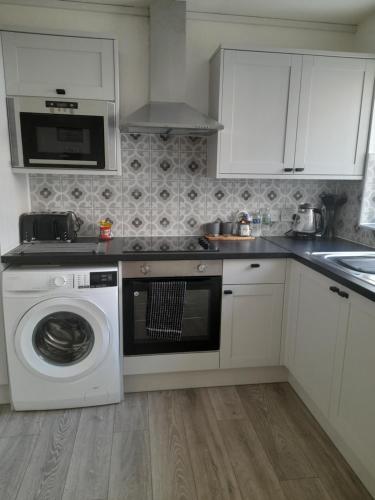a kitchen with a washing machine and a microwave at Church House in Gainsborough