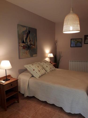 a bedroom with a bed and two lamps and a painting at Luna Menguante in Robledillo de Gata
