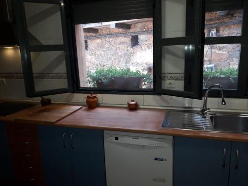 een keuken met een aanrecht met 2 ramen en een wastafel bij Luna Menguante in Robledillo de Gata