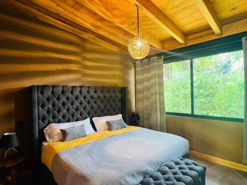 - une chambre avec un grand lit et une grande fenêtre dans l'établissement Cabaña en el bosque V14, à Godínez