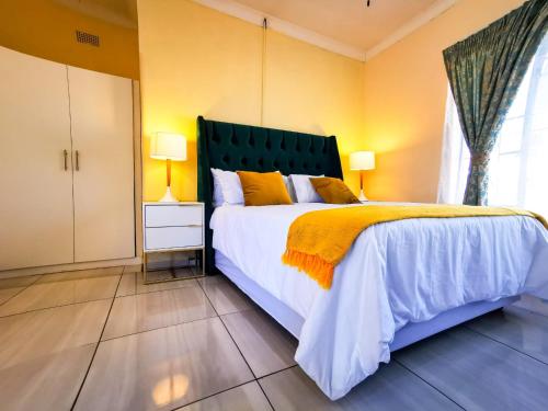 ein Schlafzimmer mit einem großen Bett und gelben Wänden in der Unterkunft Genesis Guesthouze in Bela-Bela