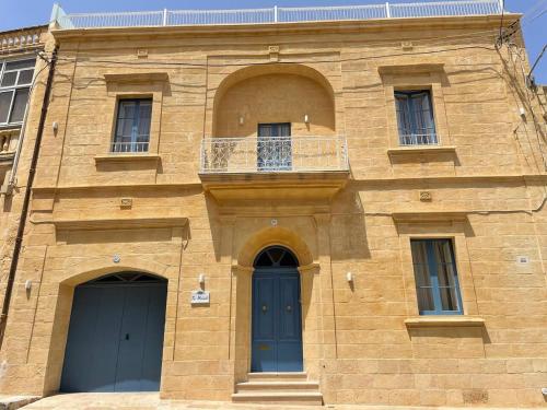 ein Gebäude mit zwei blauen Türen und einem Balkon in der Unterkunft Ta Mikieli 62 in Nadur