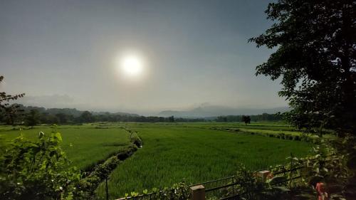 a large green field with the sun in the sky at Karjat Villa (3 BHK) With Garden Amidst Nature in Karjat