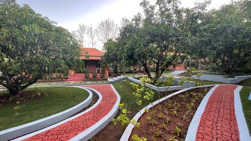 a garden with red bricks and trees and a building at Nature First Eco-Village in Dhārwād