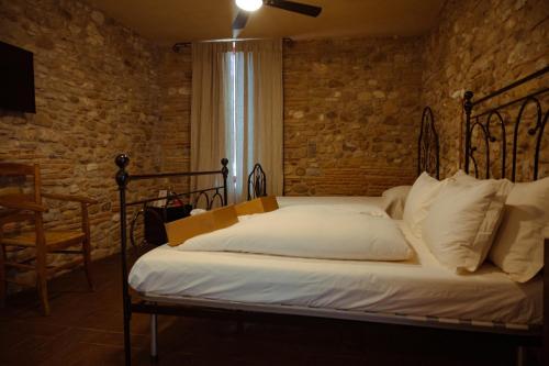 Agriturismo Podere Tovari في أنغياري: سرير في غرفة بجدار من الطوب