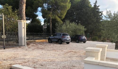 two cars parked in a parking lot next to a fence at Dimora Caraspi in Mola di Bari