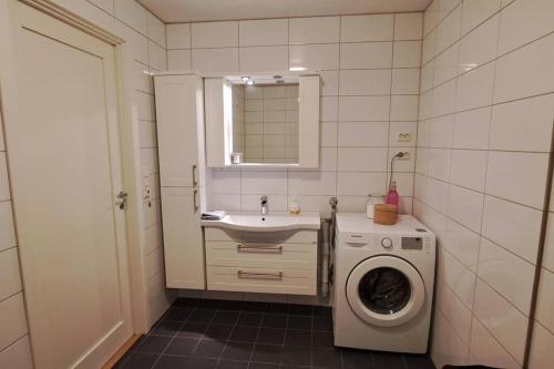 a bathroom with a washing machine and a sink at Senja, Husøy i Senja. Leilighet med utsikt over fjord og fjell in Tofta