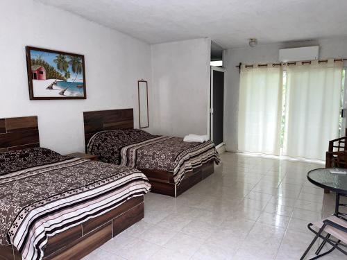 Habitación de hotel con 2 camas y mesa en Teques inn, en Tequesquitengo