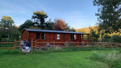 a log cabin in a field with a fence at Songbird Lodge - Near brew pub/10 mins from Snowdon in Caernarfon