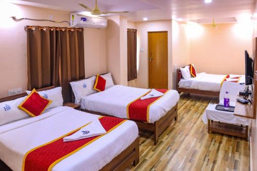 a hotel room with two beds and a television at Hotel Radha Krishna in Visakhapatnam