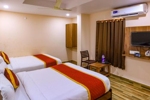 a hotel room with two beds and a tv at Hotel Radha Krishna in Visakhapatnam