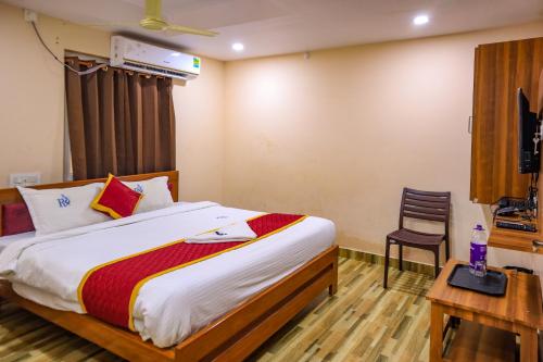 a bedroom with a bed and a table and a chair at Hotel Radha Krishna in Visakhapatnam