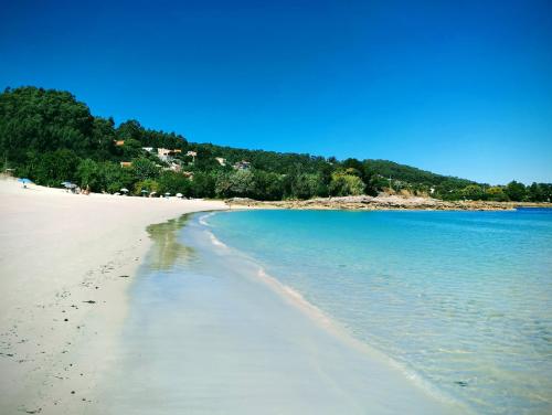 a beach with footprints in the sand and the water at CASA LAXE DO BARRO in Cangas de Morrazo