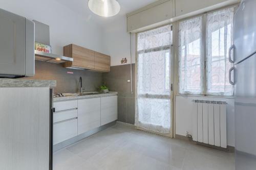 a kitchen with white cabinets and a large window at Ferrara Biscay Bay Apartment with balconies in Ferrara
