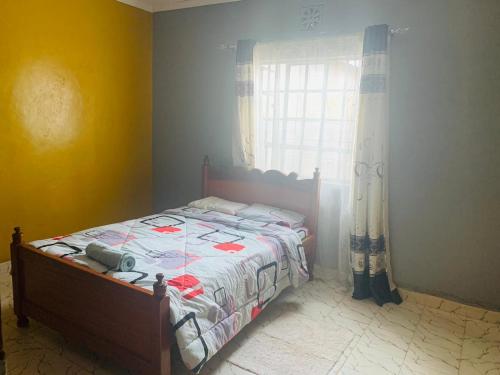 een slaapkamer met een bed en een raam bij Plush 3 Bedroom Apartment Home in Kitale