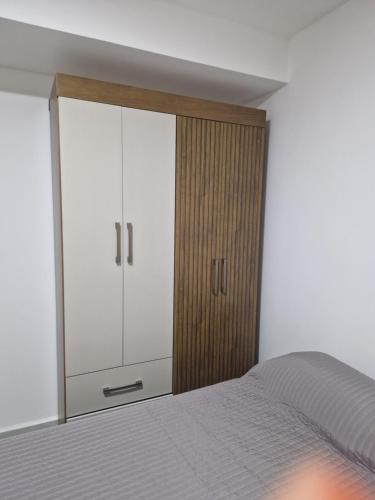 1 dormitorio con 1 cama y armario blanco en Souza Lofts Centro Praça Tiradentes en Teófilo Otoni