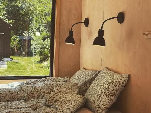 ein Schlafzimmer mit zwei Lichtern über einem Bett und einem Fenster in der Unterkunft Elevated Tiny House Glamping in Tjøme