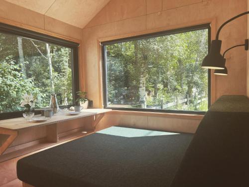 Cette chambre dispose d'une grande fenêtre, d'un bureau et d'une table. dans l'établissement Elevated Tiny House Glamping, à Tjøme