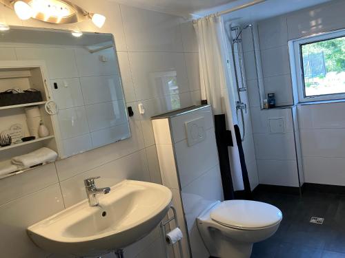 a white bathroom with a sink and a toilet at Ferienwohnung im Grünen mit Balkon in Herdecke